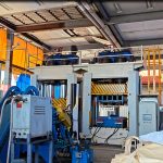 Máquina de prensado de tarimas de plástico en marcha en una planta de Japón, el molde cerrándose sobre la mezcla preparada